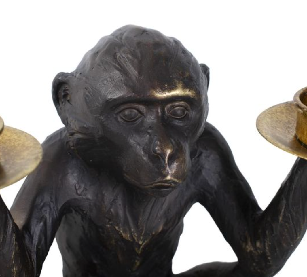 Bronze monkey figurine holding two candle holders.