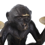 Bronze monkey figurine holding two candle holders.