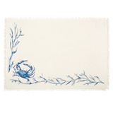 An off-white woven placemat with a blue crab and blue seaweed branch design in the lower-left corner.