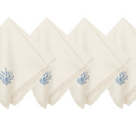 Four off-white cotton napkins with fringed edges and a small blue botanical embroidery on the corner.