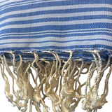 A close-up of a blue and white striped woven textile with fringed tassels along the bottom edge.