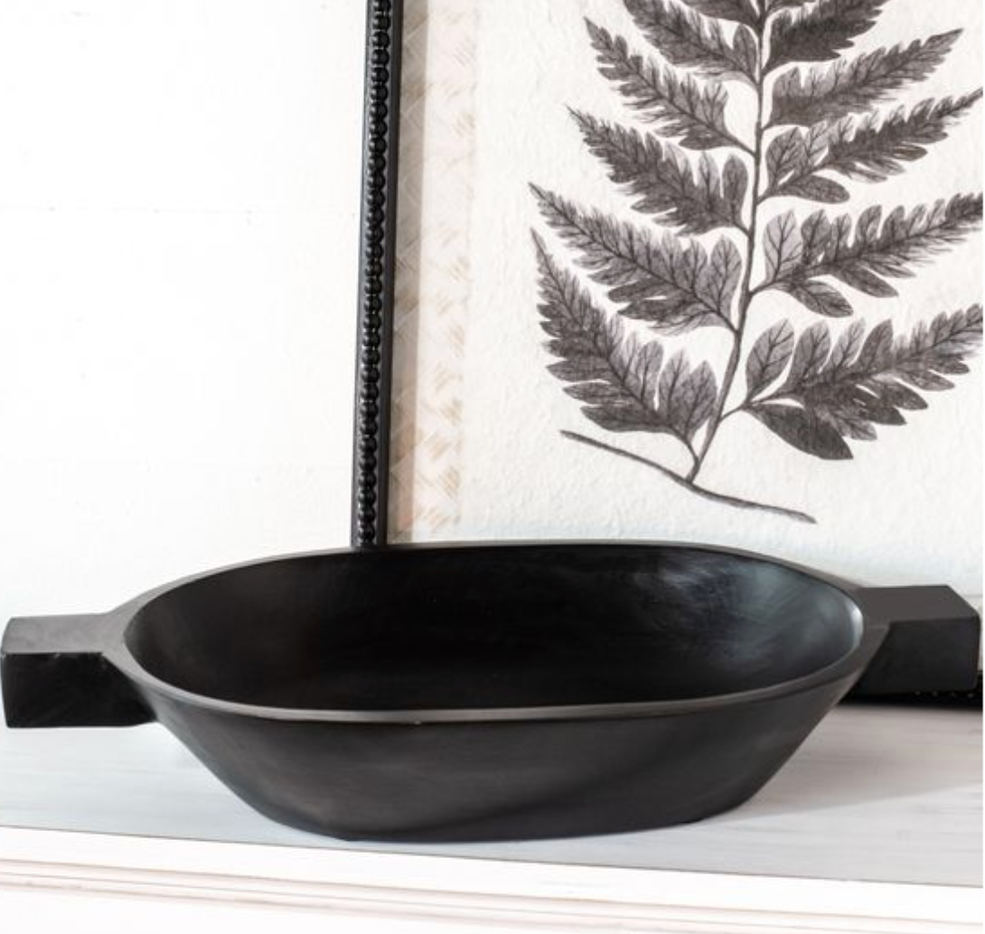 A black wooden bowl with handles displayed on a table.