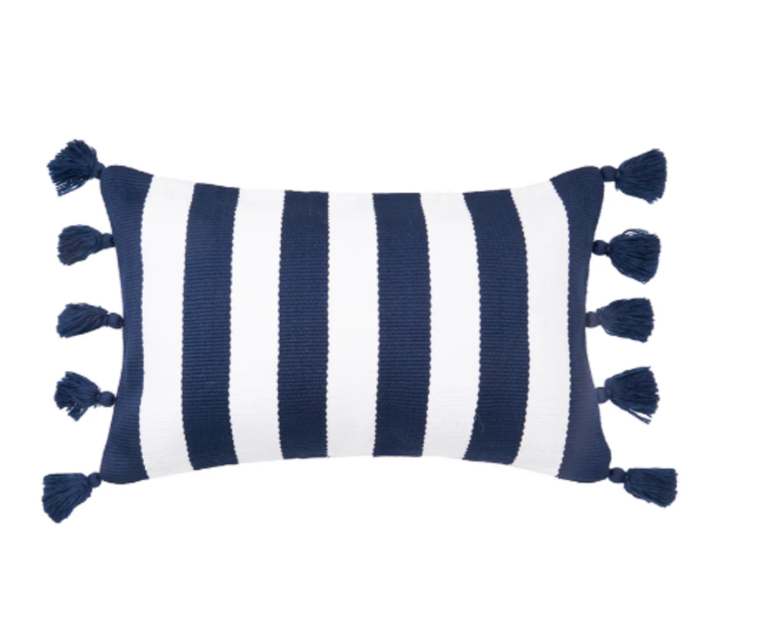 A rectangular throw pillow with vertical navy blue and white stripes and matching navy tassels on the sides,.