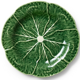 A round ceramic plate designed to look like a green cabbage leaf, featuring raised leaf veins and a small white center hole.