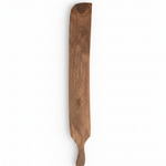 A long, narrow wooden serving board or paddle with a natural brown wood grain.