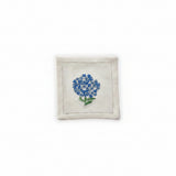 A white cotton cocktail napkin with hand embroidered blue hydrangea flowers and green leaves.