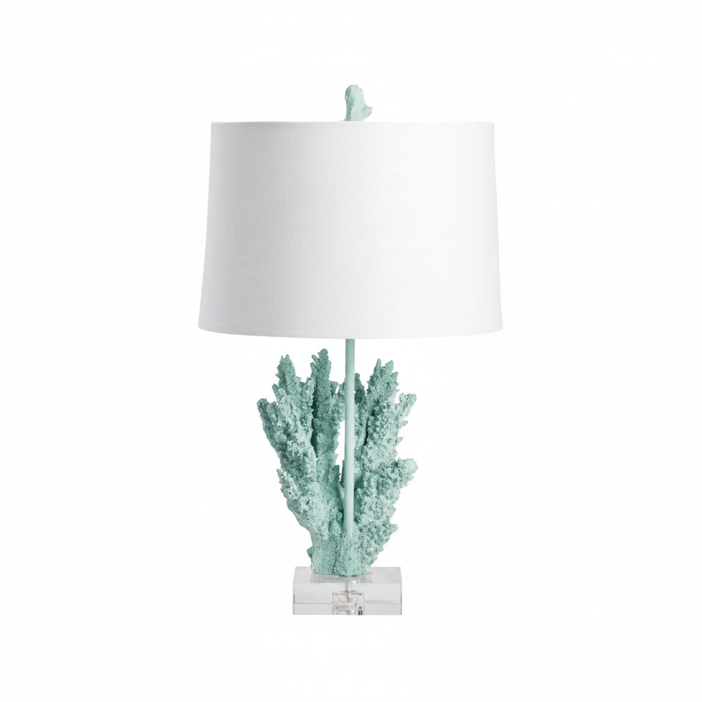 A table lamp with a blue resin and crystal base in the shape of coral, topped with a white lampshade.