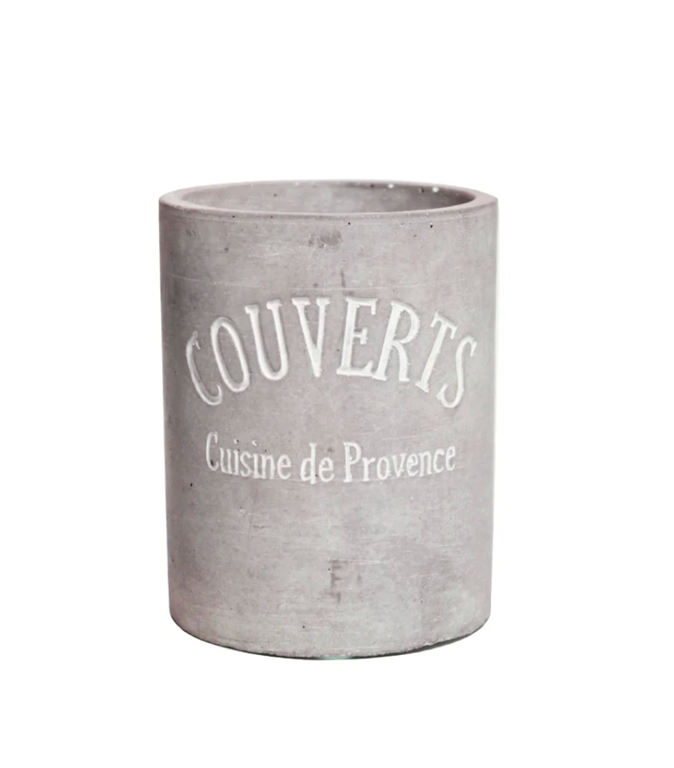A cylindrical gray concrete planter with a distressed finish, featuring the words 'COUVERTS' and 'Cuisine de Provence' printed in white on the front.