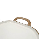 Close-up of a white oval tray or platter with a textured tan woven handle.