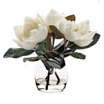 Artificial white magnolia flowers arranged in a clear glass vase.