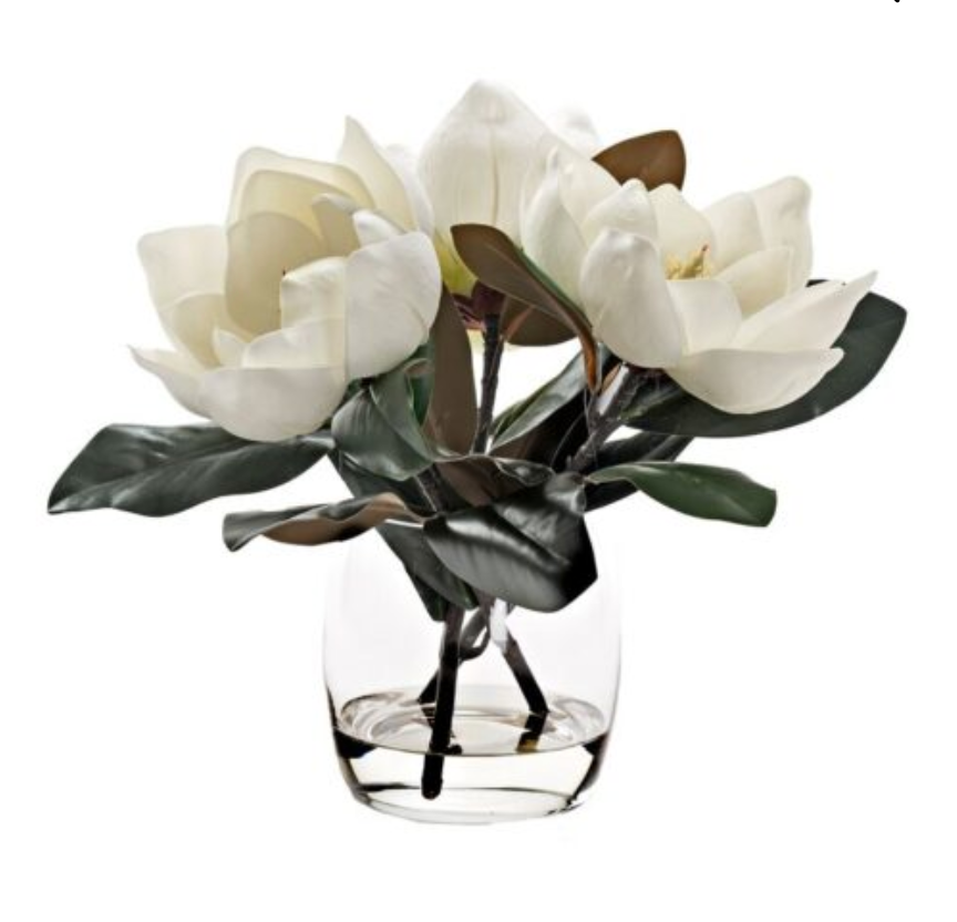 Artificial white magnolia flowers arranged in a clear glass vase.