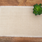 A rectangular natural jute placemat with fringed edges.