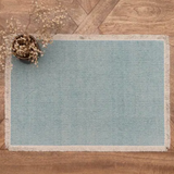 A rectangular light blue woven rug with a natural beige fringed border.