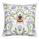 A square decorative throw pillow with an embroidered botanical pattern of blue flowers, green leaves, and a central bumblebee motif.