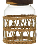 A clear glass jar with a dark brown wooden lid and a natural woven rattan or wicker sleeve around the body.