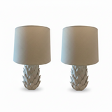 A table lamp with a sculptural, petal-like white base and a large drum shade