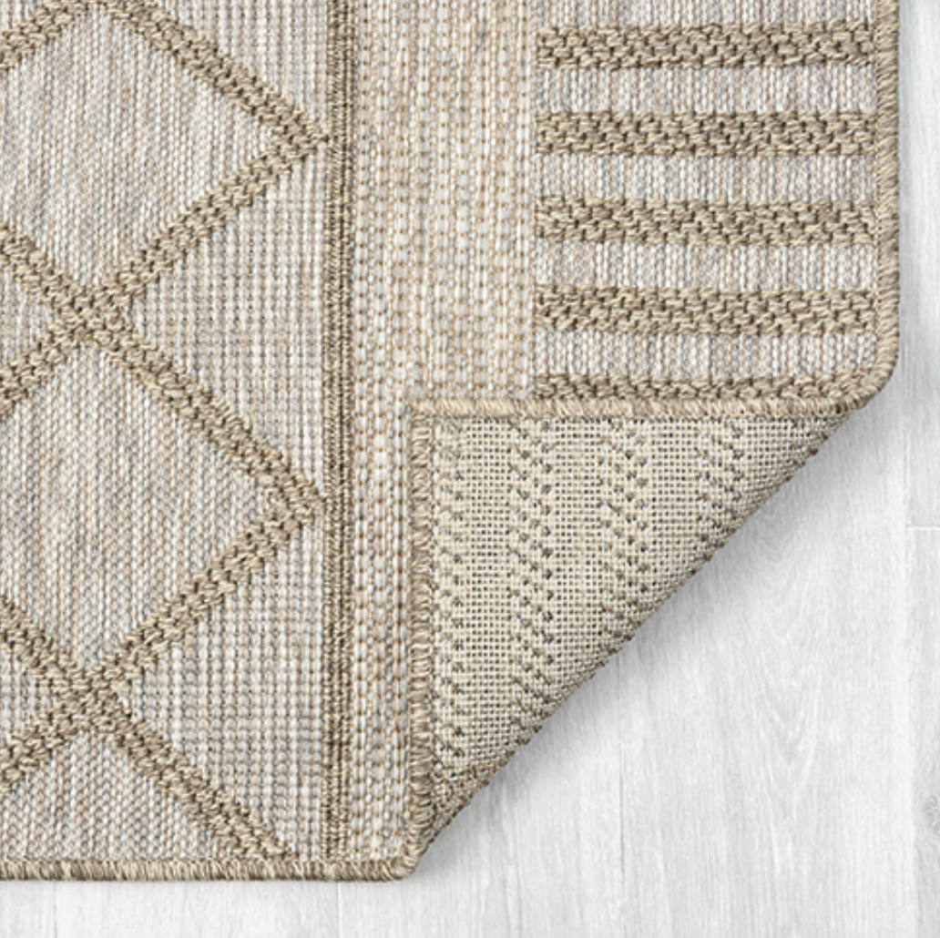Close-up of a textured beige and brown rug with geometric patterns.