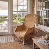 A tall, high-back woven rattan armchair with a natural tan finish.
