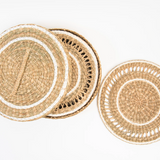 Three round woven seagrass placemats in natural beige and white tones.