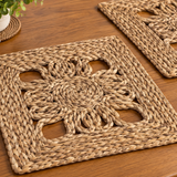Two woven natural fiber placemats with a floral cutout pattern.