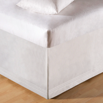 Close-up of a white bed with a fitted sheet.