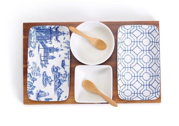 A set of porcelain and bamboo serving pieces with a blue floral pattern, including two bowls, two rectangular plates, and one acacia wood tray.