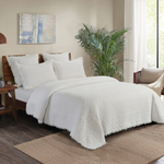 White textured comforter on a bed.