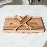 Two hand-carved wooden serving spoons with a natural wood grain finish, crossed over each other.