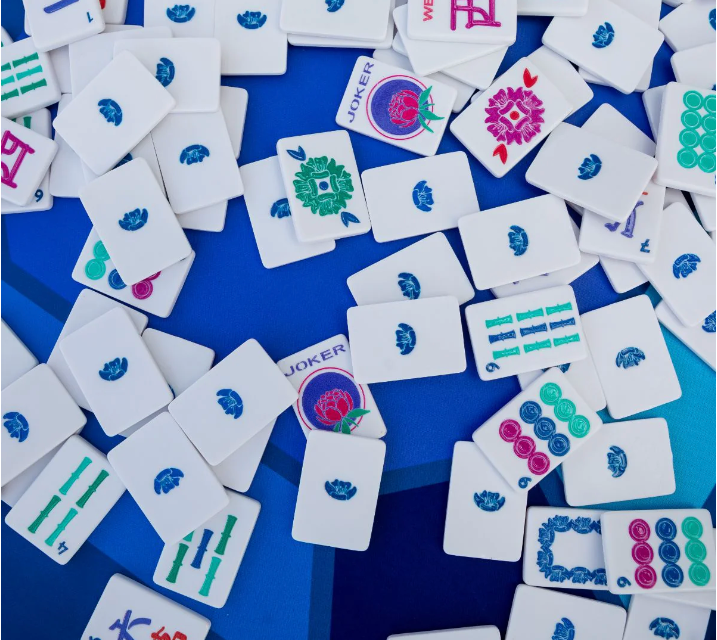 Assorted mahjong tiles on a blue surface.